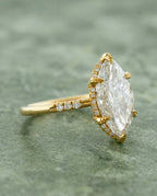 Three-quarter profile view of a 4 CT marquise lab grown diamond ring in yellow gold with leaf-textured prongs and hidden halo.