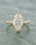 Top-down view of a 4 CT marquise lab diamond engagement ring held by six leaf-engraved yellow gold prongs.