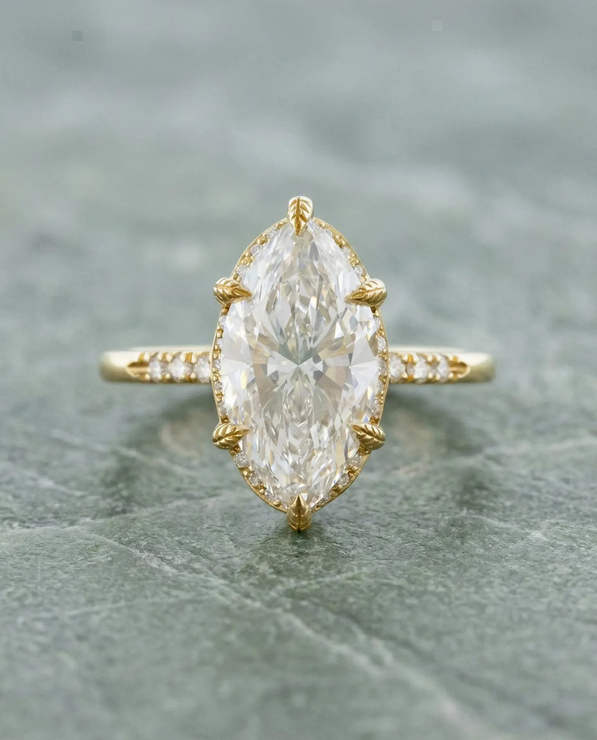 Top-down view of a 4 CT marquise lab diamond engagement ring held by six leaf-engraved yellow gold prongs.