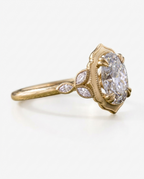 Side profile view of a 4 CT oval lab grown diamond ring in yellow gold with scalloped milgrain frame and leaf side accents.