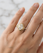Top-down view of a 4 CT oval lab diamond vintage engagement ring on hand in yellow gold.