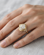 On-hand view of a 4 CT oval lab grown diamond vintage ring with scalloped frame and leaf side accents in yellow gold.