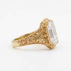 Side view of a 5 CT emerald cut lab grown diamond ring in yellow gold with hand-engraved vintage filigree shank.