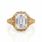 Overhead top view of a 5 CT emerald cut lab diamond ring set in yellow gold with scalloped milgrain bezel and filigree shoulders.
