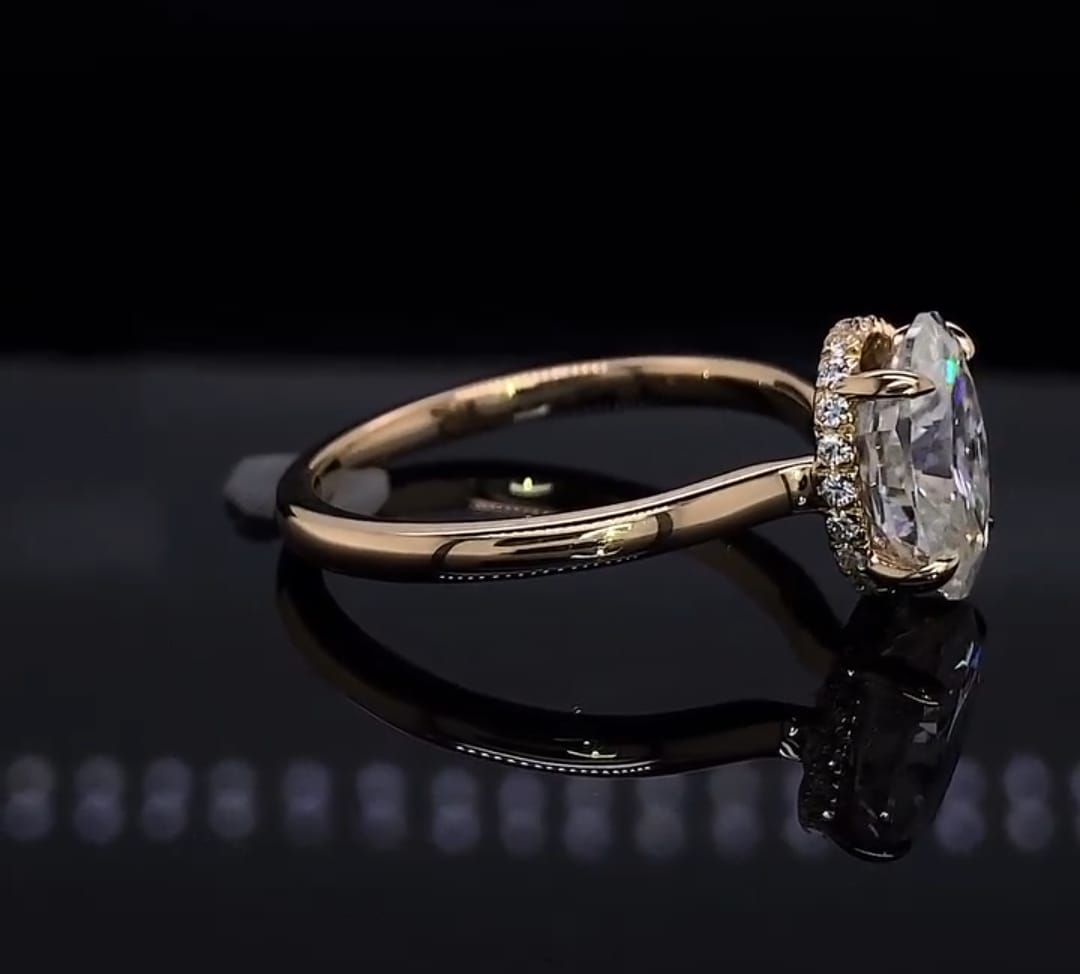 Side profile view of a gold engagement ring highlighting the exquisite hidden diamond halo holding a 2 CT oval cut diamond.