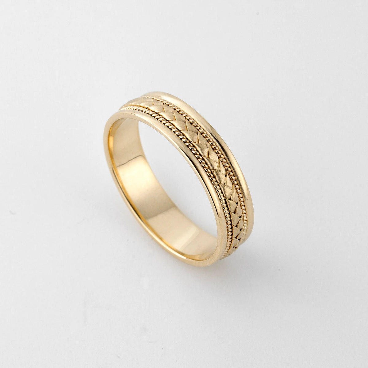 High angle perspective showing the inner comfort-fit polish and outer woven detailing of a men's gold wedding ring.