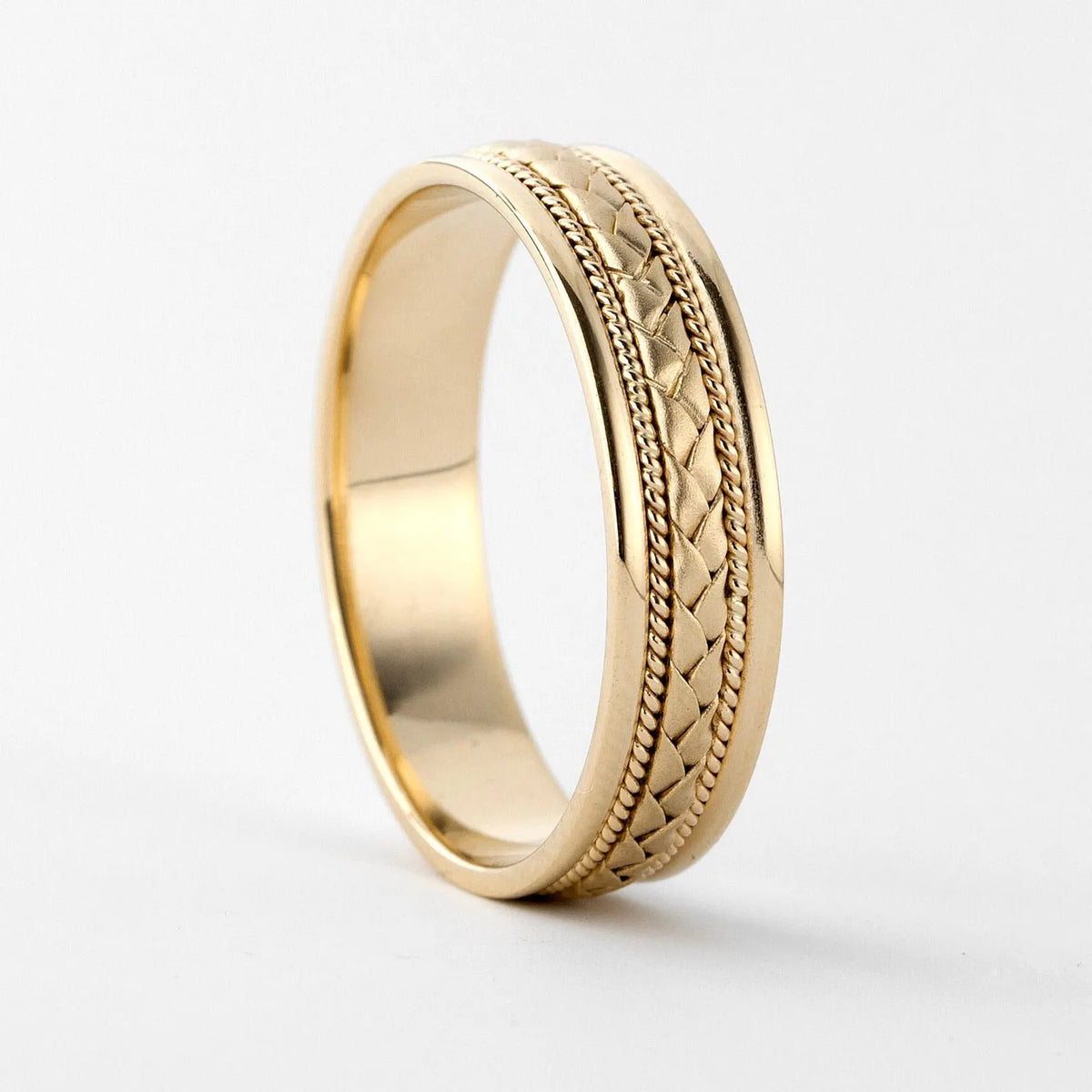 Side perspective view of a men's yellow gold wedding band with braided center weave and twisted cable edges.