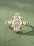 Top view of a 4 CT marquise cut lab grown diamond engagement ring in yellow gold featuring claw prongs, pear side stones, and an engraved band.