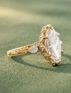Angled side view of a 4 CT marquise cut lab grown diamond ring with pear-cut side accent diamonds and sculpted claw prongs.