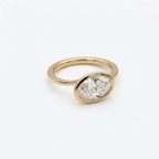 Three-quarter view of a 2 CT east-west oval cut lab grown diamond engagement ring set in a polished yellow gold bezel frame.