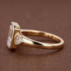 Side angle view of a 5 CT radiant cut lab grown diamond engagement ring in a yellow gold bezel setting with trillion side stones.