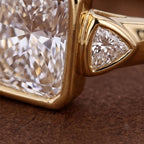 Close-up detail of a 5 CT radiant cut lab diamond and bezel-set trillion accent diamond in yellow gold.