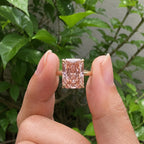 Close-up view of a 4 CT fancy pink radiant cut lab diamond solitaire held between fingers in natural light.