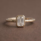 Front studio view of a 2 CT emerald cut lab grown diamond solitaire ring in a yellow gold full bezel setting.