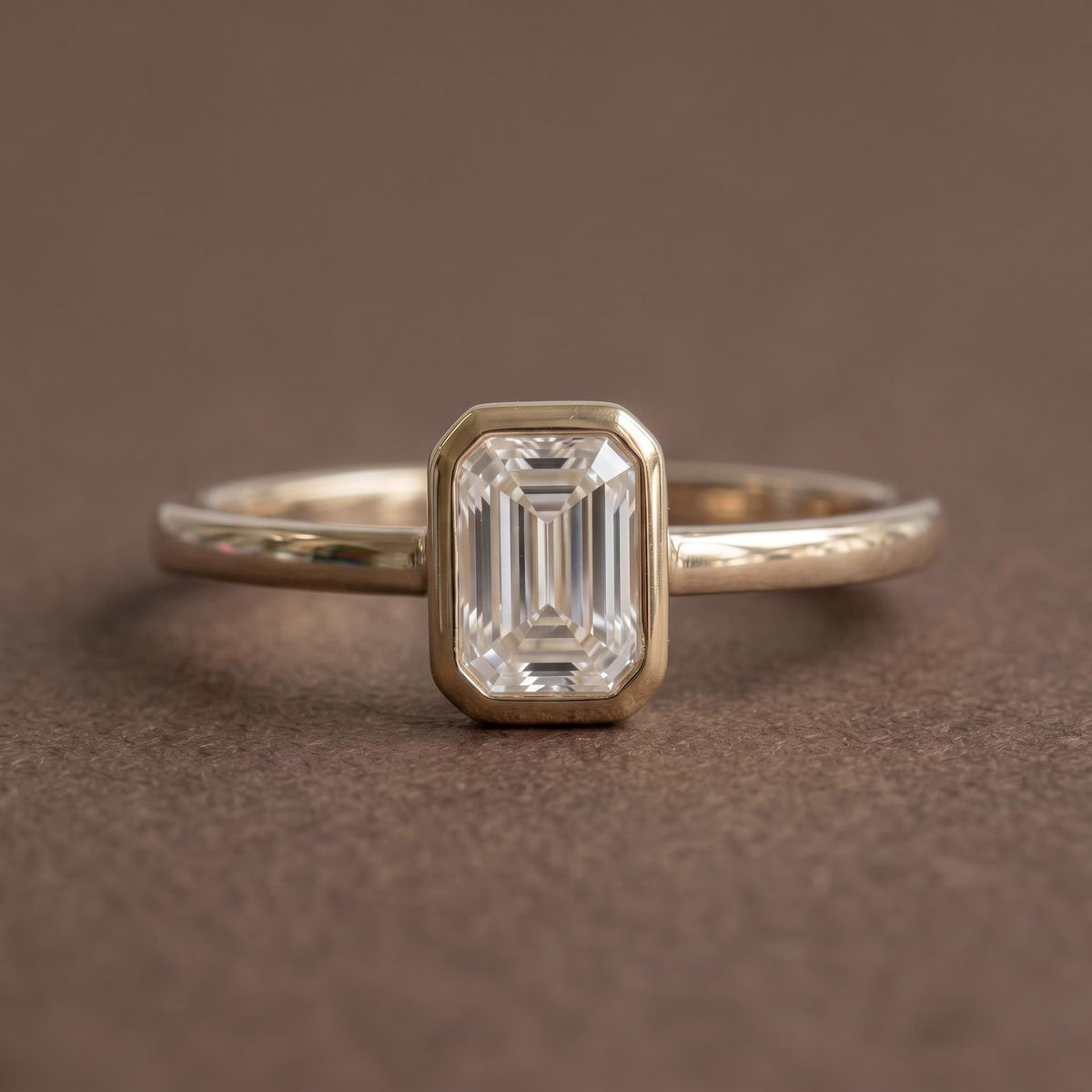 Front studio view of a 2 CT emerald cut lab grown diamond solitaire ring in a yellow gold full bezel setting.