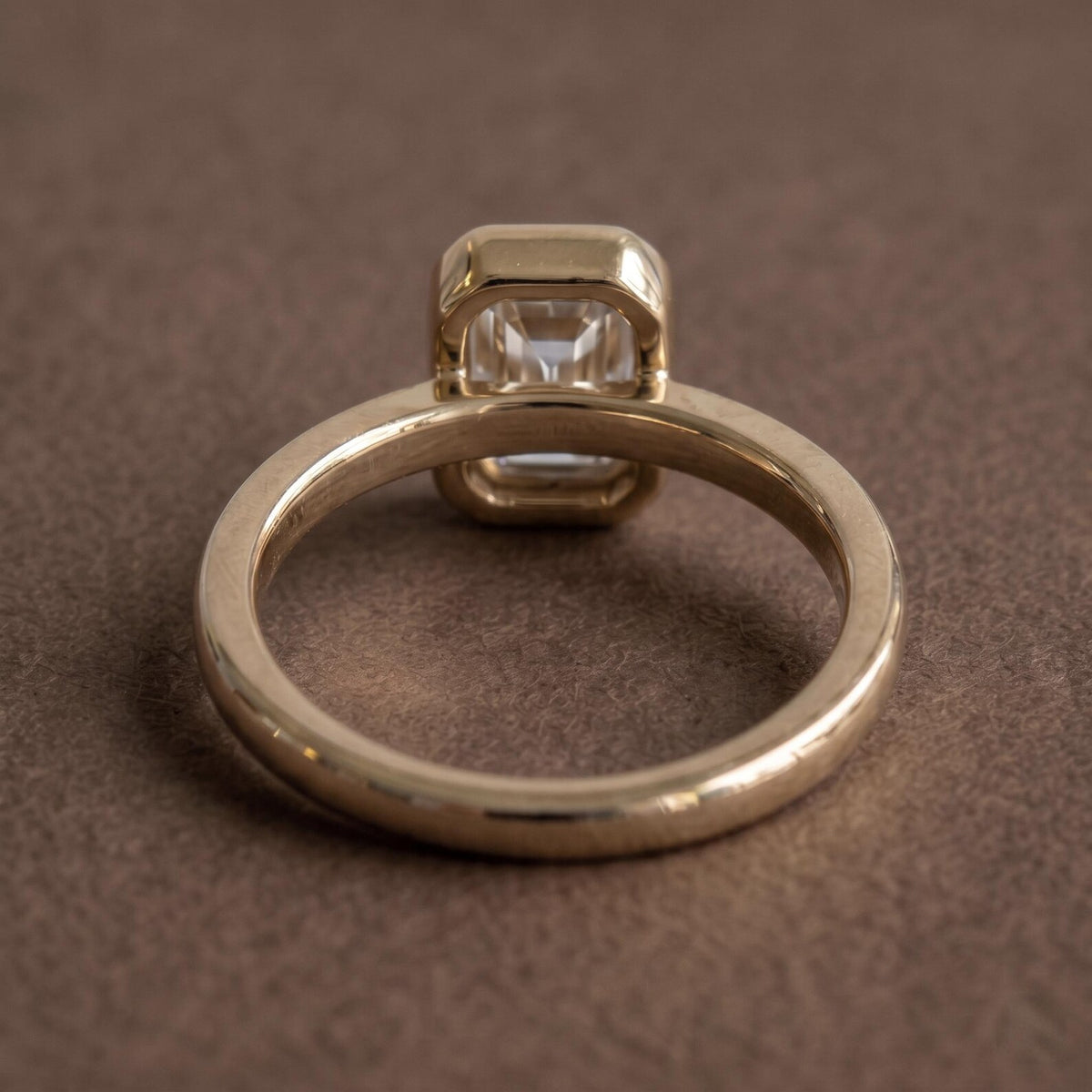 Bottom view of a 2 CT emerald cut lab grown diamond bezel engagement ring showing band architecture and undergallery.