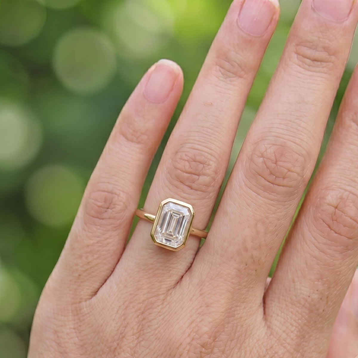 Direct top-down view of a 2 CT emerald cut lab grown diamond ring in a protective yellow gold bezel setting.