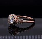 Angled top view highlighting the smooth bezel setting and accent diamonds embedded in the antique-style shoulders of the rose gold ring.