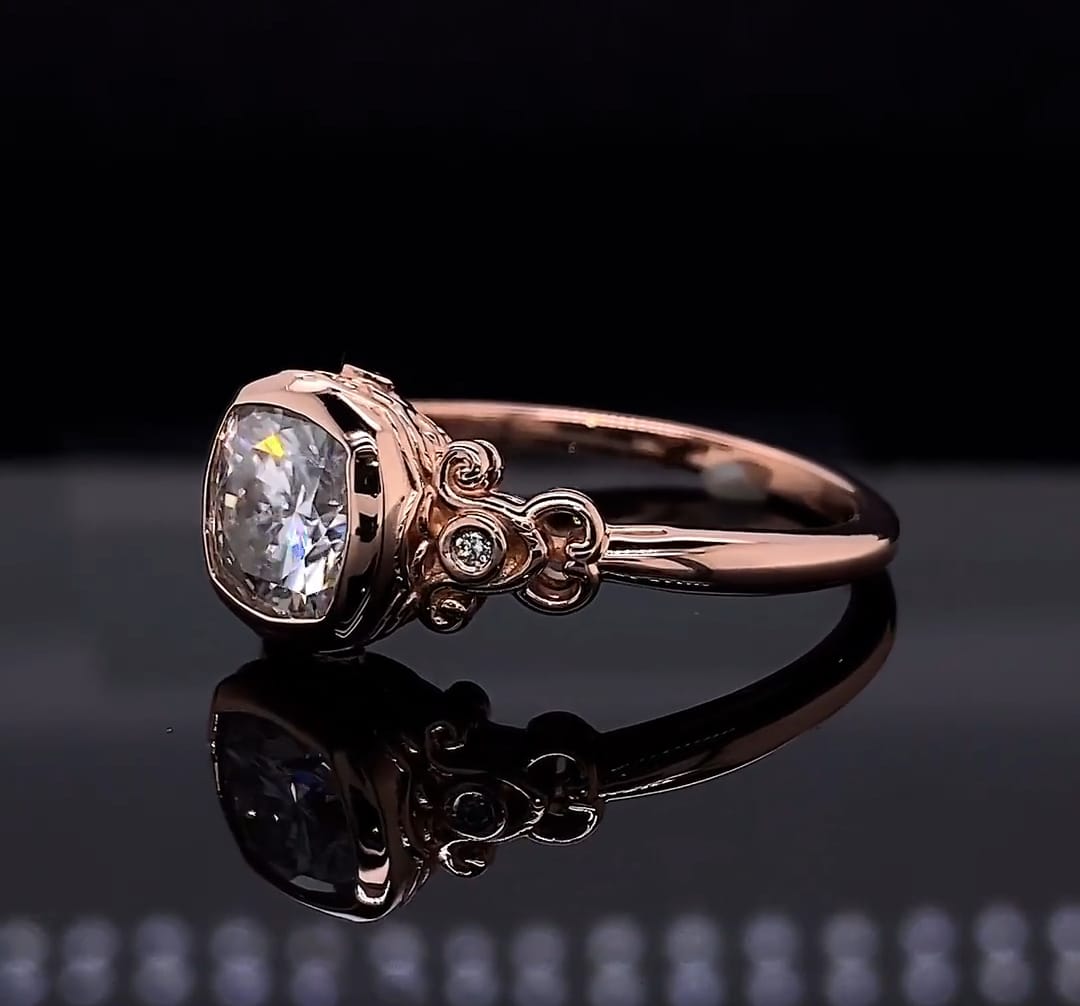 Angled top view highlighting the smooth bezel setting and accent diamonds embedded in the antique-style shoulders of the rose gold ring.
