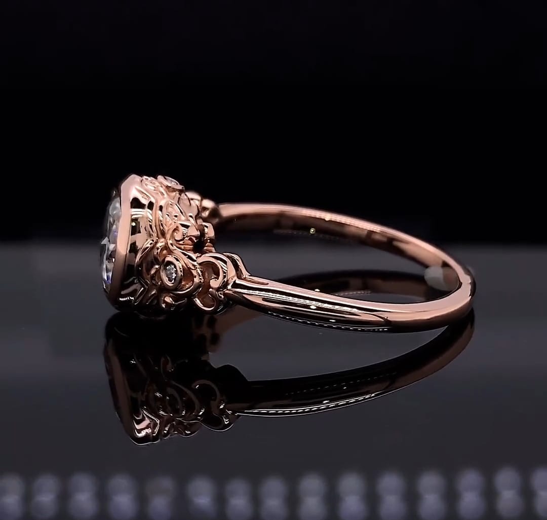 Low angle profile view detailing the intricate floral scrollwork, side diamond accents, and secure bezel setting of a cushion cut engagement ring.