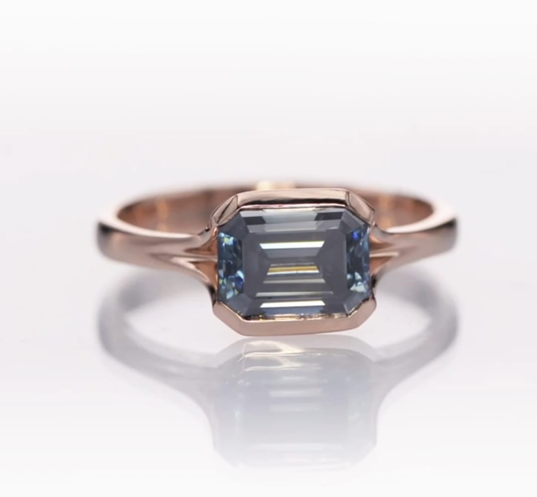 Top-down view of the 2 CT grey emerald cut moissanite gemstone framed in rose gold.