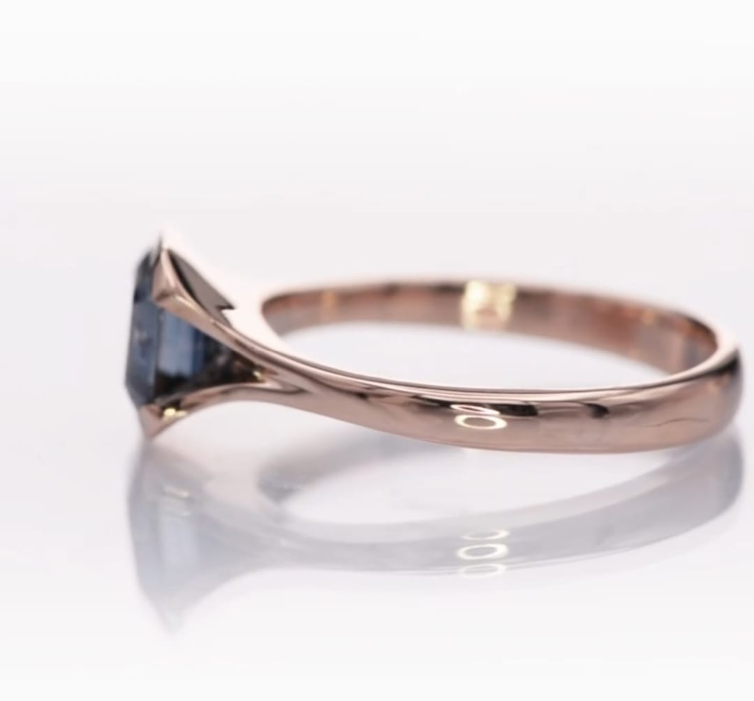 Clean side profile view of the bezel-set grey moissanite stone and tapered band.