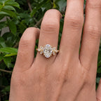 Direct top-down view on hand showing 3 CT oval center diamond and leaf cluster side accents.