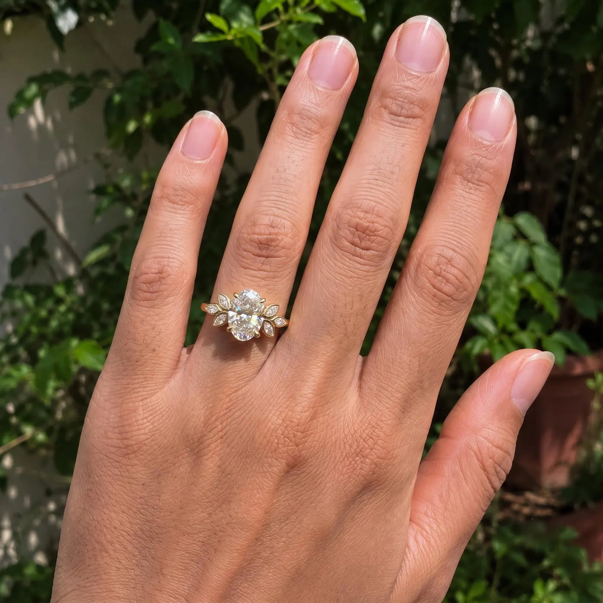 Full hand view displaying a 3 CT oval lab diamond engagement ring with nature-inspired marquise accents.