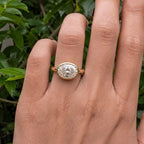 Close-up view of a 3 CT horizontal oval lab diamond bezel setting on finger in natural lighting.