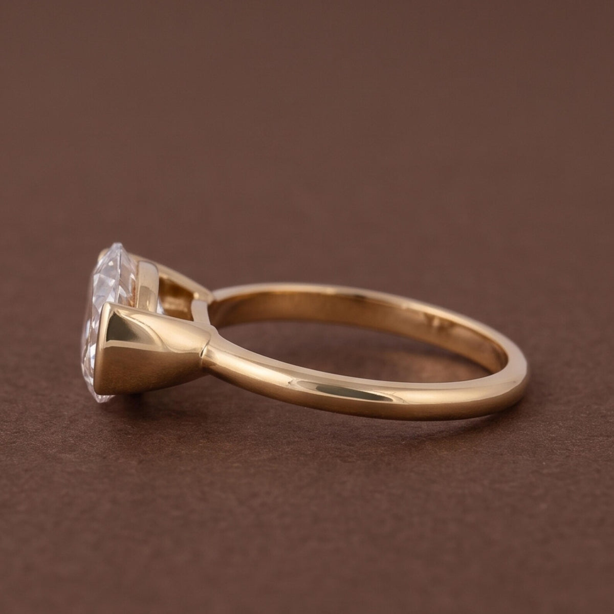 Side profile view of a yellow gold band and low-profile half-bezel setting for an oval diamond ring.