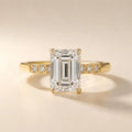 Front view of a 4 CT emerald cut lab grown diamond engagement ring with round channel-set accents on a yellow gold band.