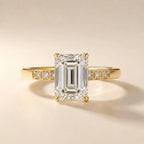 Front view of a 4 CT emerald cut lab grown diamond engagement ring with round channel-set accents on a yellow gold band.