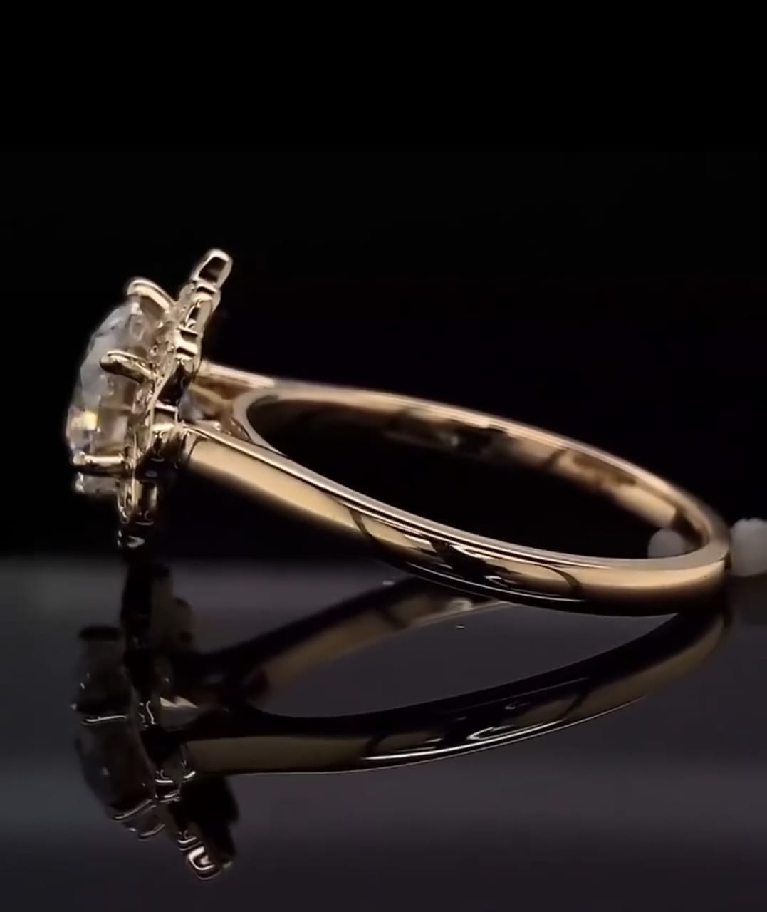 Low angle side profile of a 3 CT round diamond ring emphasizing the secure four-prong setting and high-polish plain metal shank against a black background.