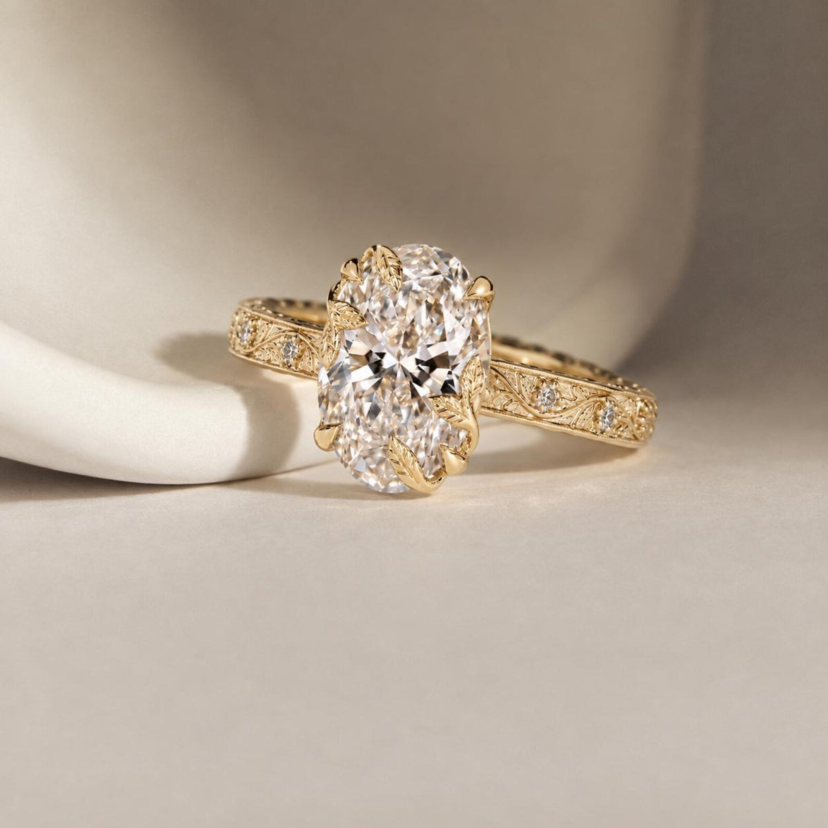 Studio perspective view highlighting the 4 CT oval cut lab diamond held by organic leaf claws on an engraved yellow gold band.