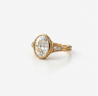 Angled side view of a 4 CT oval lab grown diamond ring with a yellow gold full bezel setting and round side accent stones.