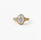 Front view of a 4 CT oval lab diamond surrounded by a protective gold bezel with side accent diamonds.