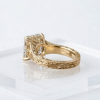 Undergallery view of a 4 CT radiant cut lab grown diamond ring with hand-engraved leaf pattern and milgrain border on a yellow gold band.