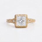 Front top view of a 4 CT princess cut lab diamond set in an engraved yellow gold bezel frame with shoulder accents.