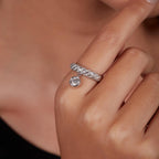 On-hand lifestyle view of a white gold dangling round lab grown diamond charm ring on a finger.