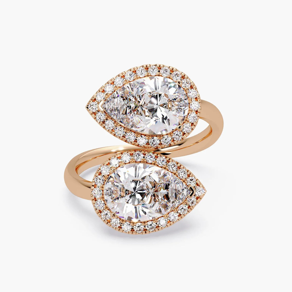 Side profile view of a yellow gold bypass ring displaying the raised halo basket setting for pear lab diamonds.