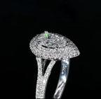 High angle side profile of a 3 CT pear cut lab grown diamond ring showcasing a raised double halo and a diamond-encrusted split shank band against a dark background.