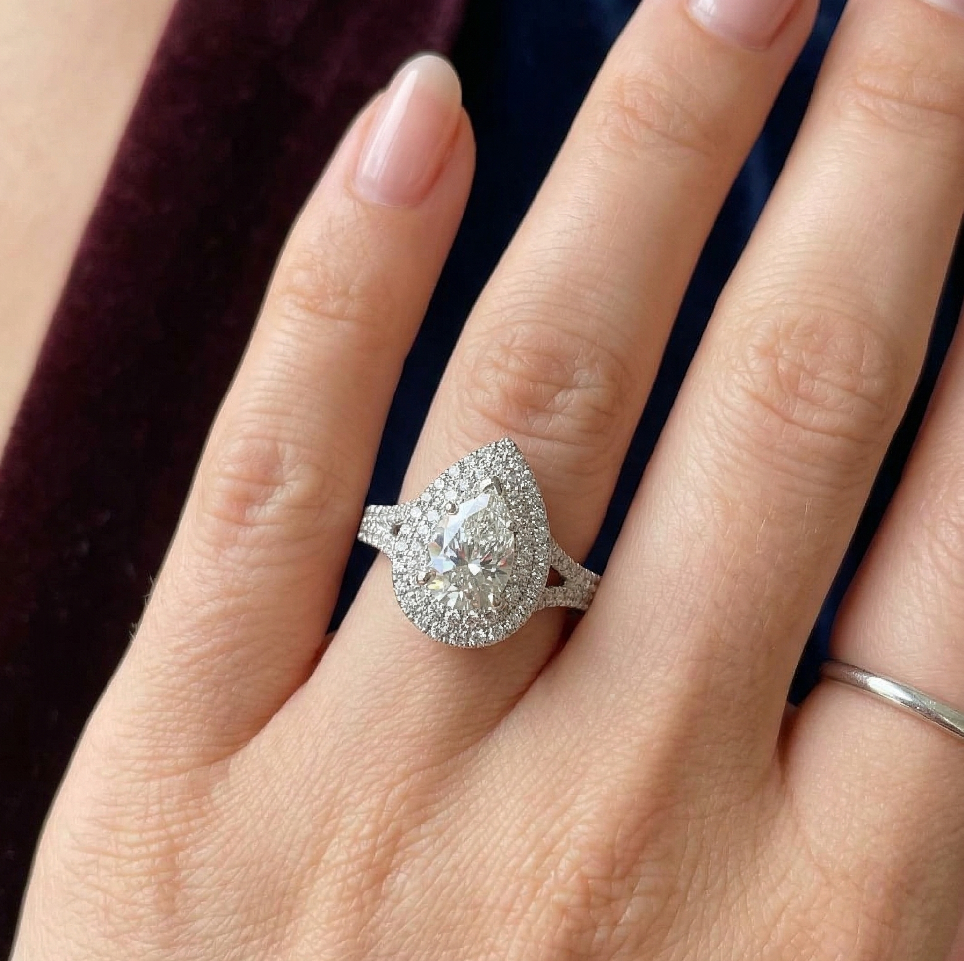 Woman's hand modeling a stunning 3 CT pear cut double halo lab grown diamond engagement ring with a split shank on the ring finger.