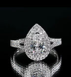 Direct top-down view of a pear cut double halo diamond engagement ring reflecting brilliantly on a dark mirror background.
