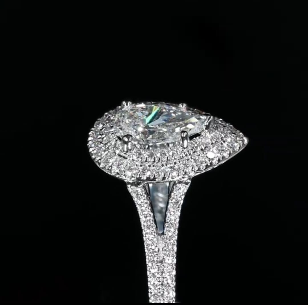 Extreme close-up side profile of a pear cut lab grown diamond highlighting the intricate prong setting, tiered double halo, and split pave band.