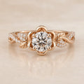 Top view of a 2 CT round cut lab grown diamond set inside a rose gold floral petal halo with leaf accents.