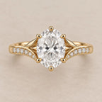Top view of a 3 CT oval cut lab grown diamond engagement ring with split leaf shoulders and pavé band in yellow gold.