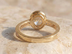 Back profile view showing the open undergallery and smooth inner band of a yellow gold bezel oval lab diamond ring.