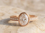 Front view of a 3 CT oval cut lab grown diamond bezel set engagement ring in warm rose gold.