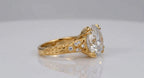 Side profile of a 4 CT round lab diamond set with double claw prongs on a hand-engraved leaf pattern yellow gold shank.