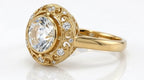 Close-up front angled view of a vintage-inspired 4 CT round lab diamond ring with openwork swirl halo and milgrain borders.